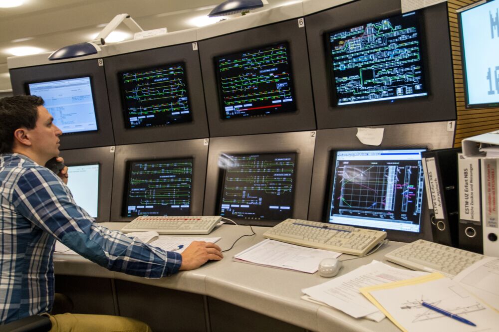 Ein Mann sitzt vor vielen Bildschirmen, die virtuelle Gleisnetze zeigen.