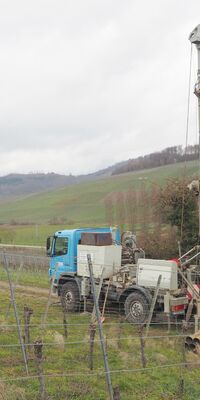 Ein LKW-montiertes Bohrgerät steht am Fuße eines Weinbergs.