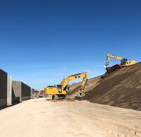 Bagger arbeiten an einem Hang neben einer Schallschutzwand.