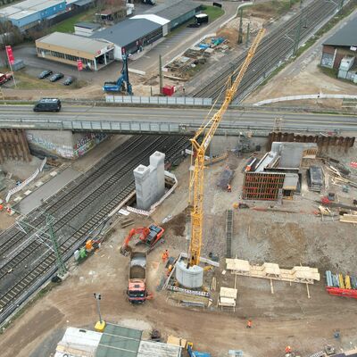 Eine Straßenbrücke über Gleise. Im Vordergrund eine Brückenbaustelle.