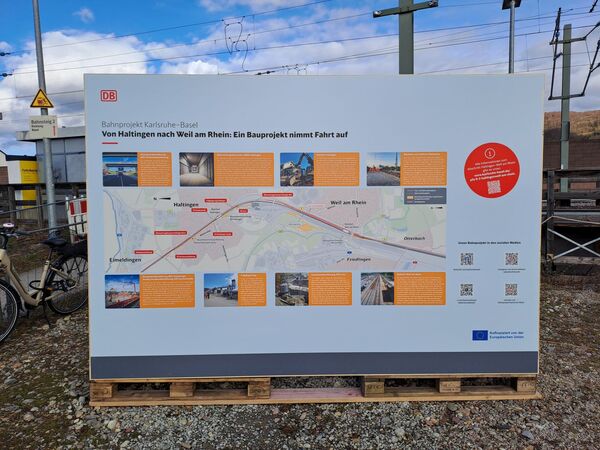 Infotafel zu Baumaßnahmen in Haltingen und Weil am Rhein, im Hintergrund blauer Himmel