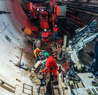 Ein Tunnel, in dem vier Arbeiter:innen mit Gerätschaften arbeiten.