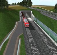 Ein Zug fährt in einen Tunnel, auf dem ein Feld liegt.