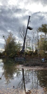 Ein Kran hebt Pontons auf einen See.