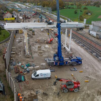 Luftbild einer Baustelle. Im Zentrum ist ein blauer Kran und ein weißer Portalkran zu erkennen