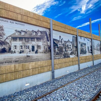 Eine Schallschutzwand mit historischem Bildern ist zu erkennen.