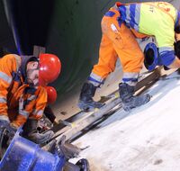 Zwei Arbeiter:innen verbinden große blaue Rohre im Tunnel.