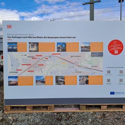 Infotafel zu Baumaßnahmen in Haltingen und Weil am Rhein, im Hintergrund blauer Himmel