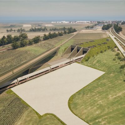 Ein Zug kommt aus einem Tunnel gefahren. Unten neben der Strecke ist ein Platz für Rettungskräfte.