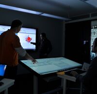 Kollaborationsraum mit digitalem Planungstisch und großem Monitor