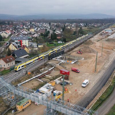 Eine Baustelle mit Tunneleingang und ein vorbeifahrender Zug.