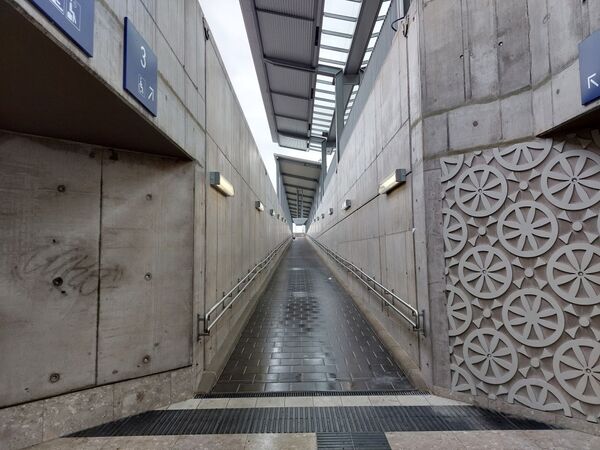 Ansteigende Rampe führt von Personenunterführung im Bahnhof Müllheim zum Bahnsteig, rechts mit Ornamenten gestaltete Betonwand