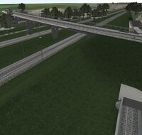 Rechts neben einer Brücke und vier Bahngleisen führt ein Eisenbahntunnel entlang.