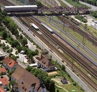 Ein Bahnhof von oben und Schallschutzwände zwischen mehreren Gleisen.