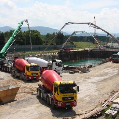 Eine Baustelle mit großem Wasserbecken und Betonmischern.
