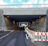 Eine Straßenunterführung. Auf der rechten Straßenseite sind noch Absperrwände zu sehen.