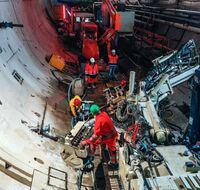 Ein Tunnel, in dem vier Arbeiter:innen mit Gerätschaften arbeiten.