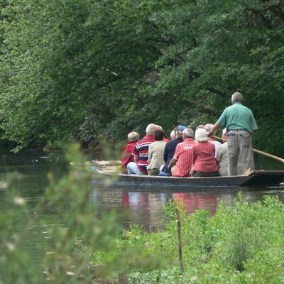 Ein Ruderboot mit Menschen auf einem Fluss.