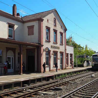 Ein Zug fährt in einen Haltepunkt mit Haus ein.