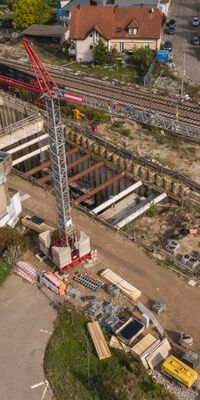 Ein Tunnelschacht neben einem großen Gebäude und Bahngleisen.