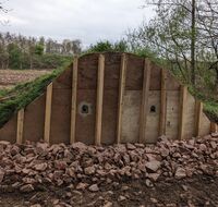 Eine Holzwand mit Löchern, die für Vögel zum Brüten dienen.