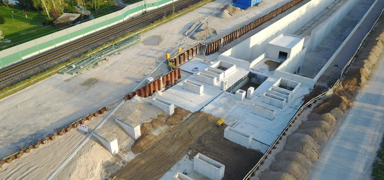 Die Lüftungsschlitze der Haubenbauwerke am Tunnel Rastatt ragen etwa einen Meter über den Boden. (Foto: DB AG/Sebastian Roedig) Haubenbauwerk mit Lüftungsschlitzen über Tunnelausgang, dahinter eine Baustelle und Gleise