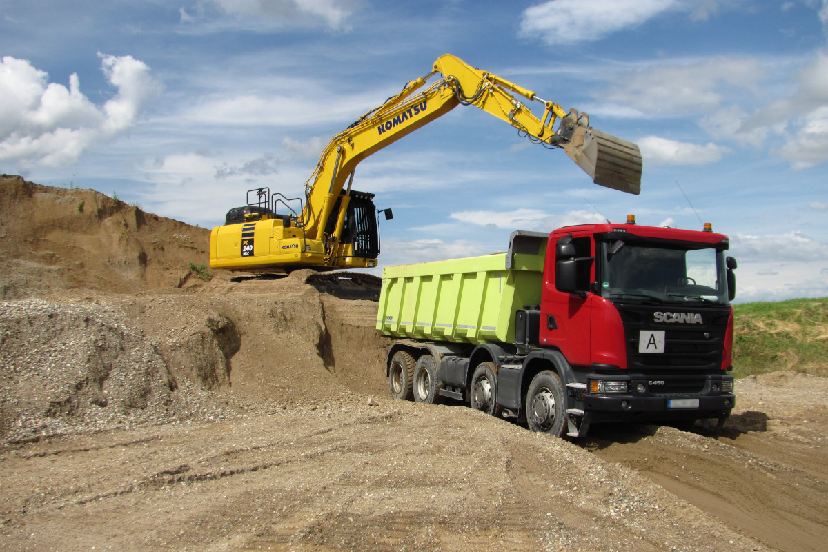 Bagger auf einer Baustelle belädt einen Kipplaster mit Aushubmaterial