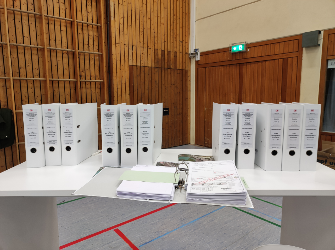 Weißer Tisch mit weißen Aktenordnern in einer Turnhalle