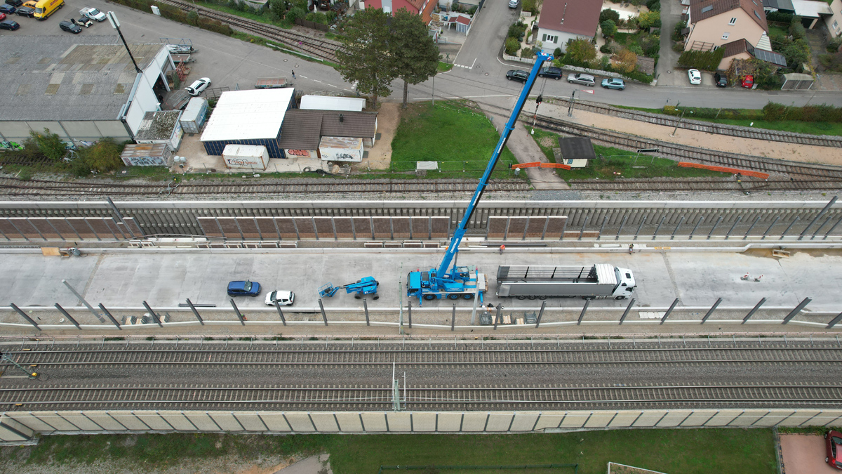 Eine Baustelle an einem Gleis. In der Mitte steht ein blauer Kran.