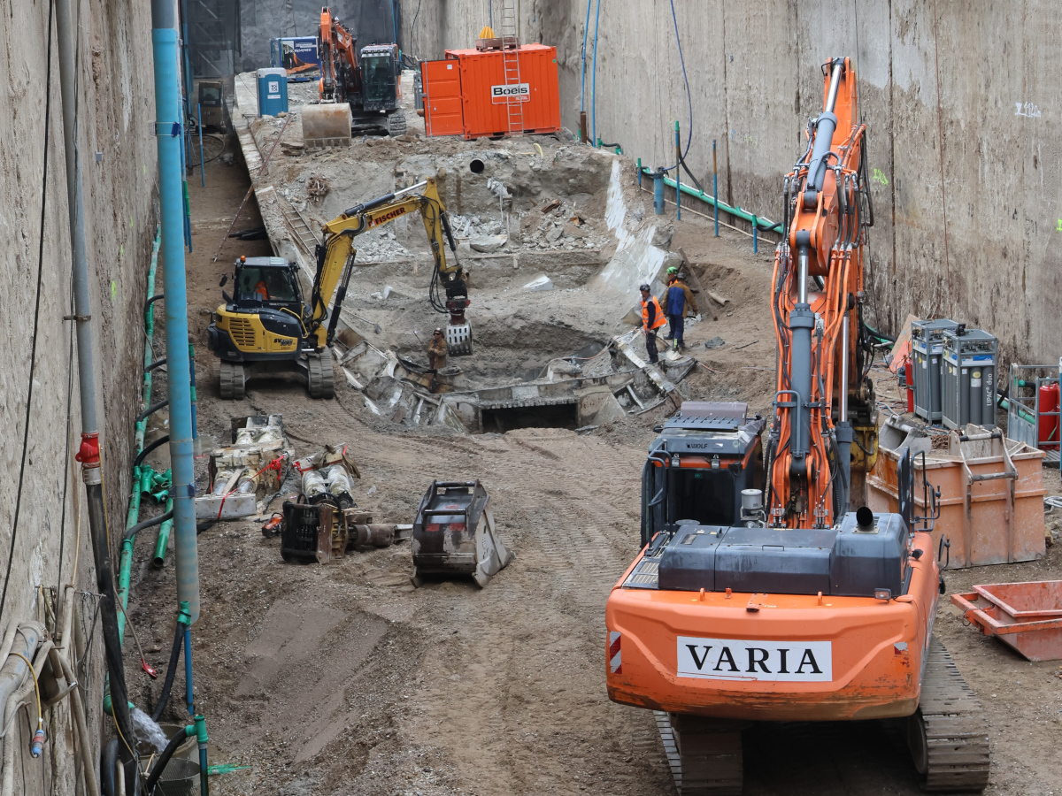 Ein orangener Bagger steht vor einer zurückgebauten TVM.